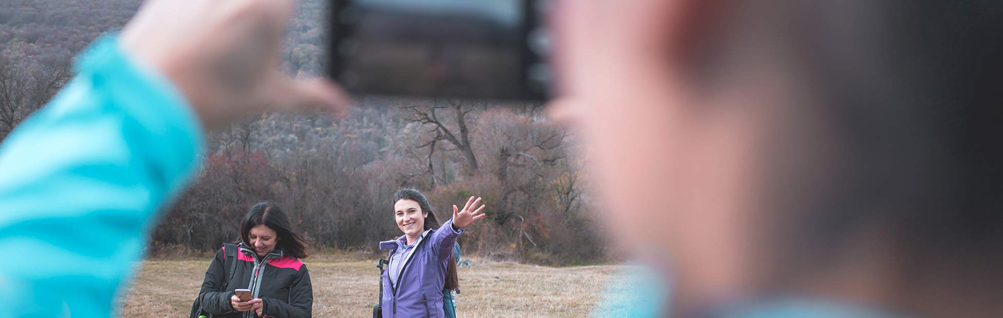 A group of female hikers taking photos and navigating via apps with their cell phones while hiking outdoors