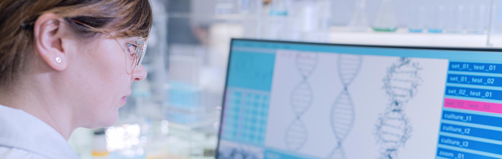 A medical geneticist studying the DNA sequence visible on the screen.