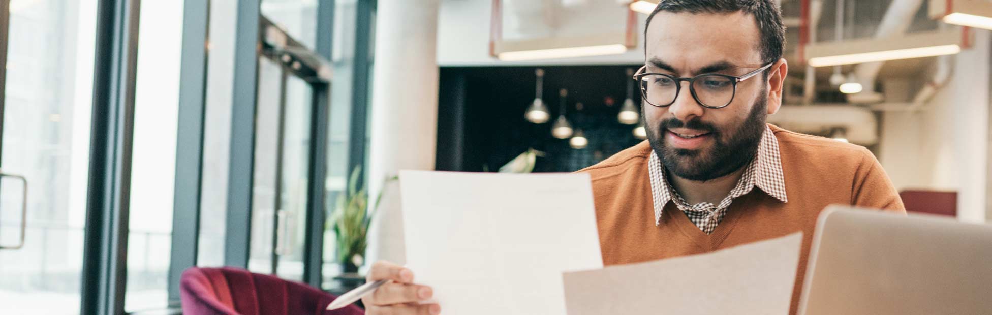 Man reviewing papers in front of laptop