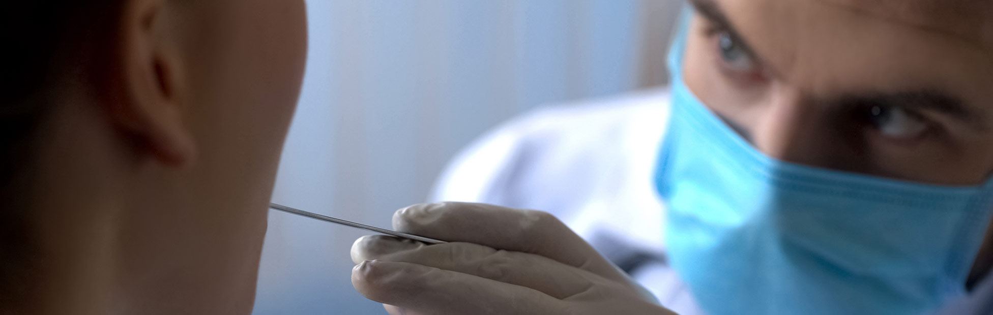 An otolaryngologist examining a female patient throat