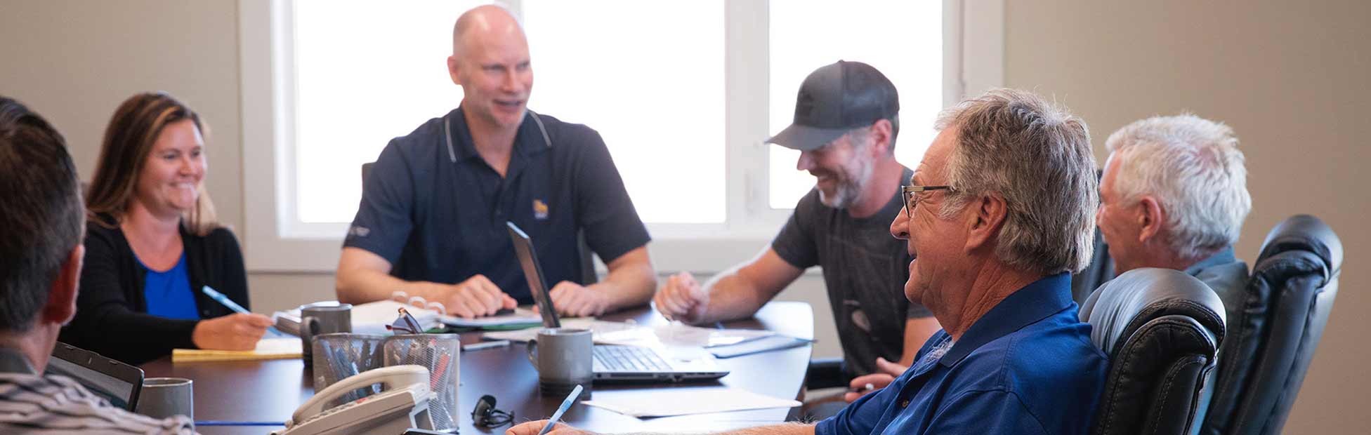 A group of farm managers and employees smiling around a conference table.