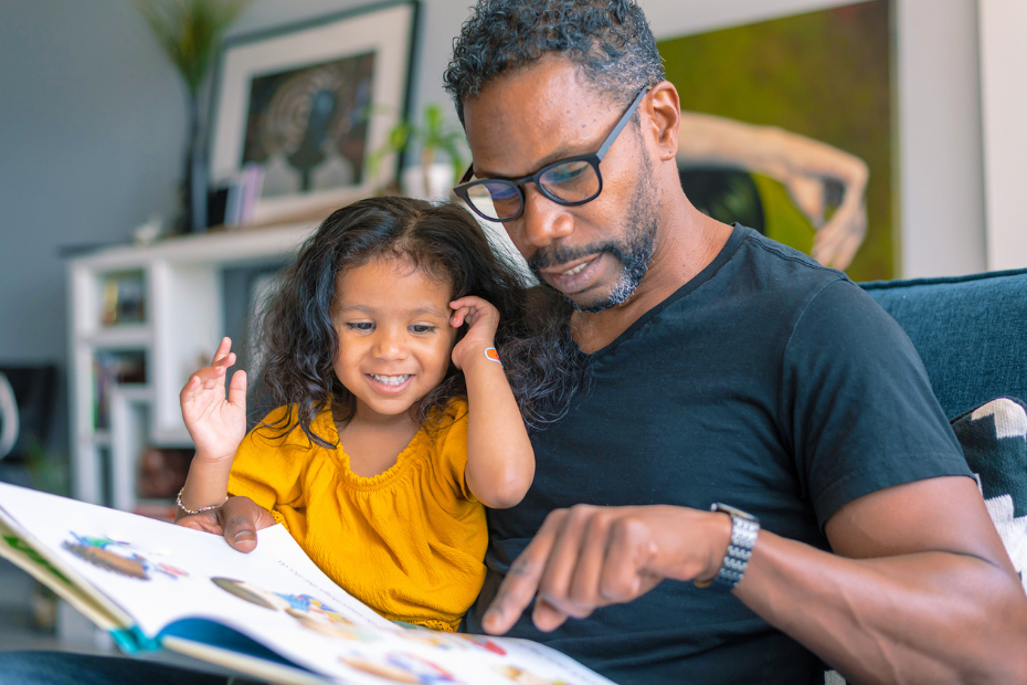 A father reading a book to his daughter