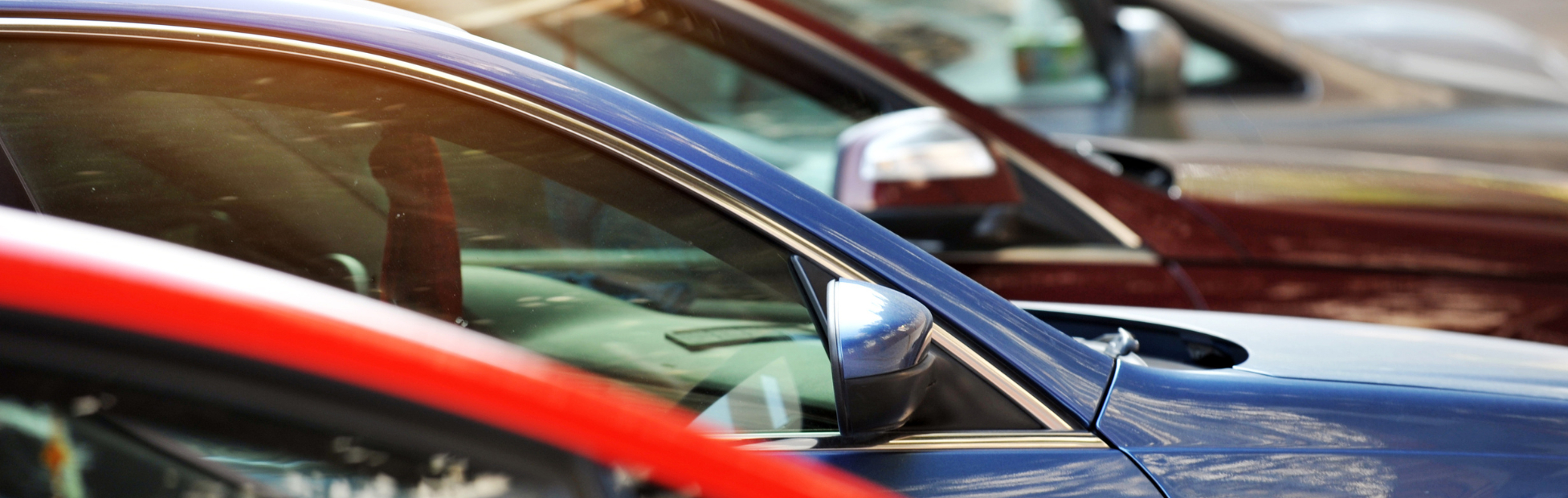 A group of cars in various colours parked in a row