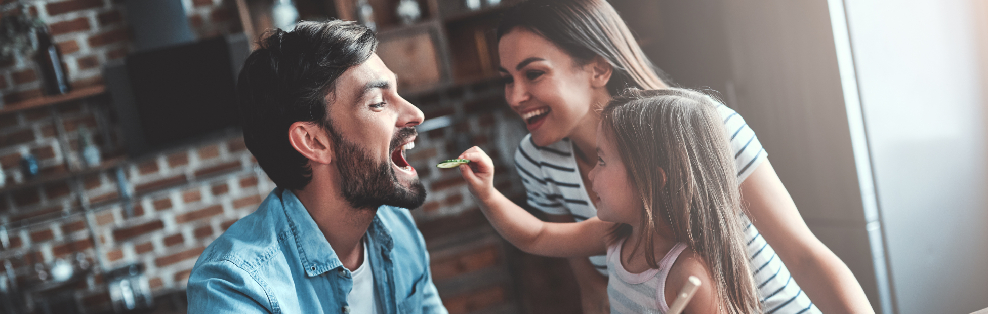 A father, mother & daughter making dinner in the kitchen together.