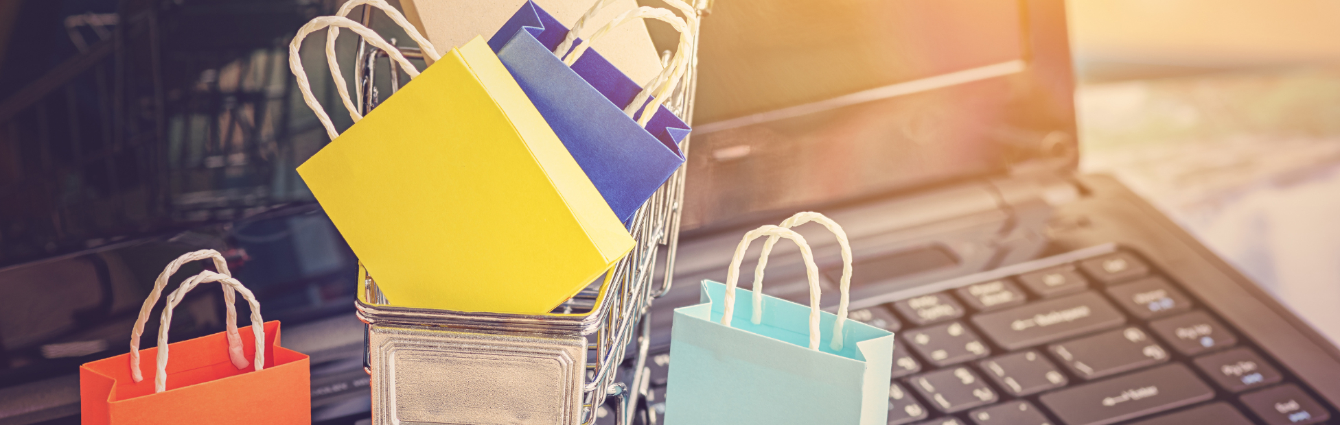Colourful mini-shopping bags sitting on a laptop