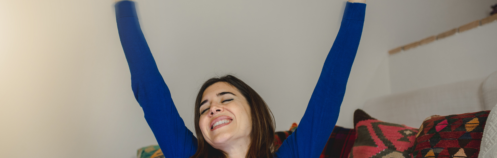 Woman with arms joyfully in the air, holding credit cards in hand