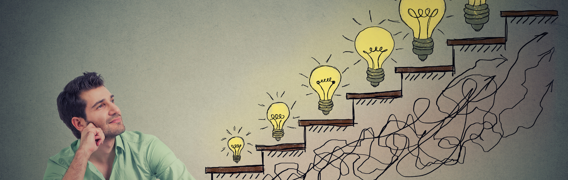 Image of a man sitting looking at a virtual wall of ideas with lightbulbs at each step