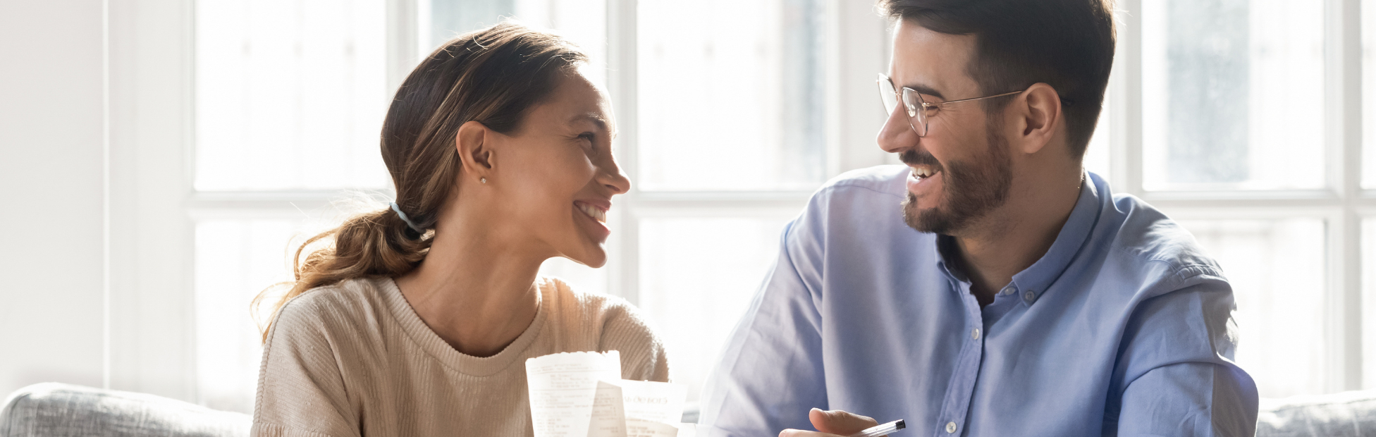 A smiling couple on a couch, working on a budget