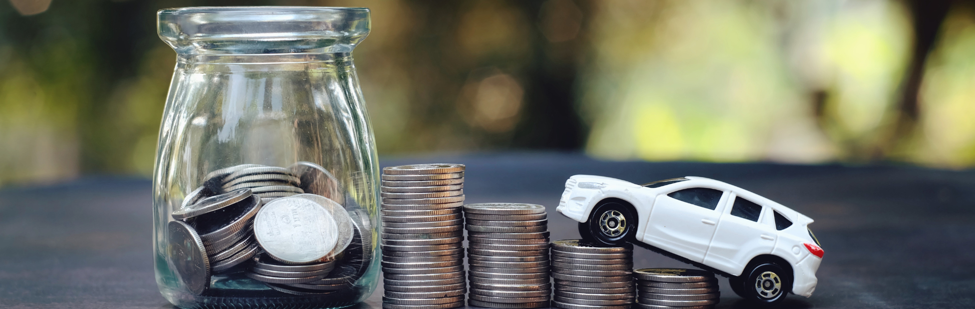 Series of stacked coins and toy car driving up the stacked coins on table