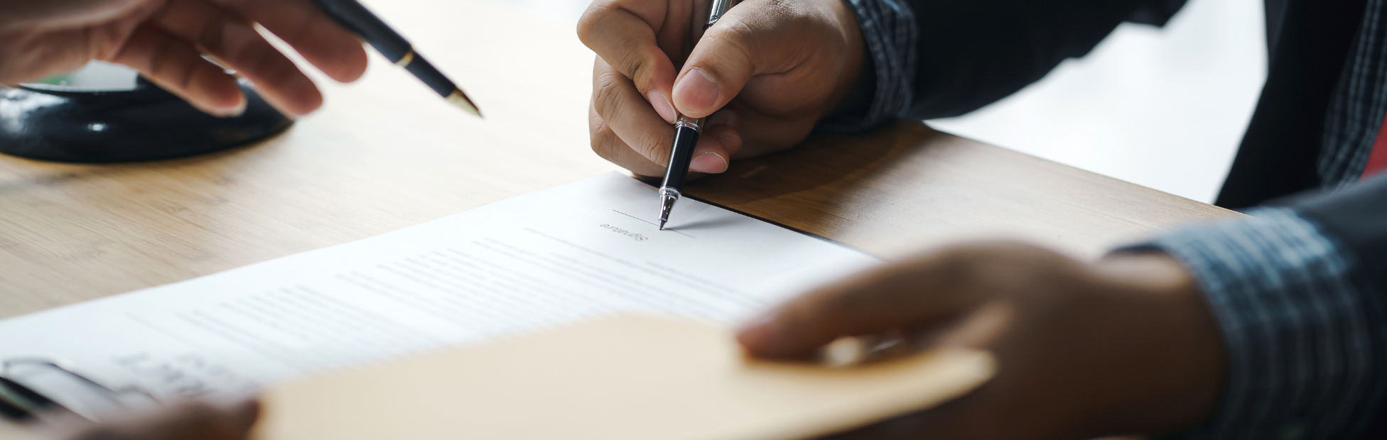 Legal support with an individual signing papers at a desk