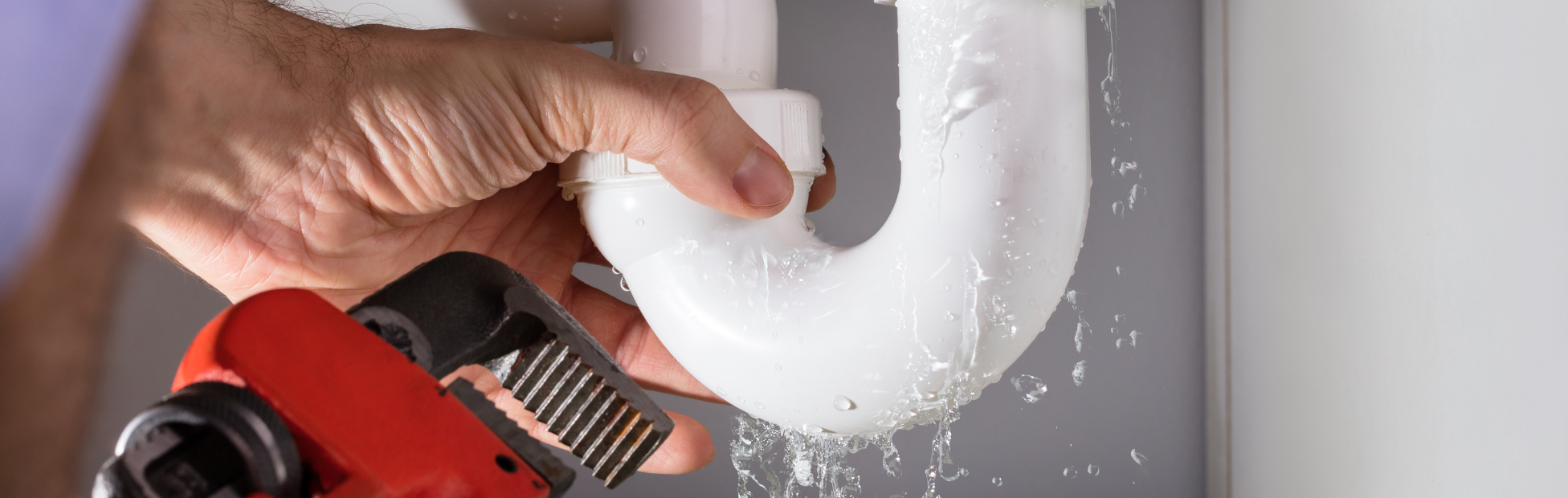 Male Plumber Fixing Dripping Sink Pipe With Adjustable Wrench