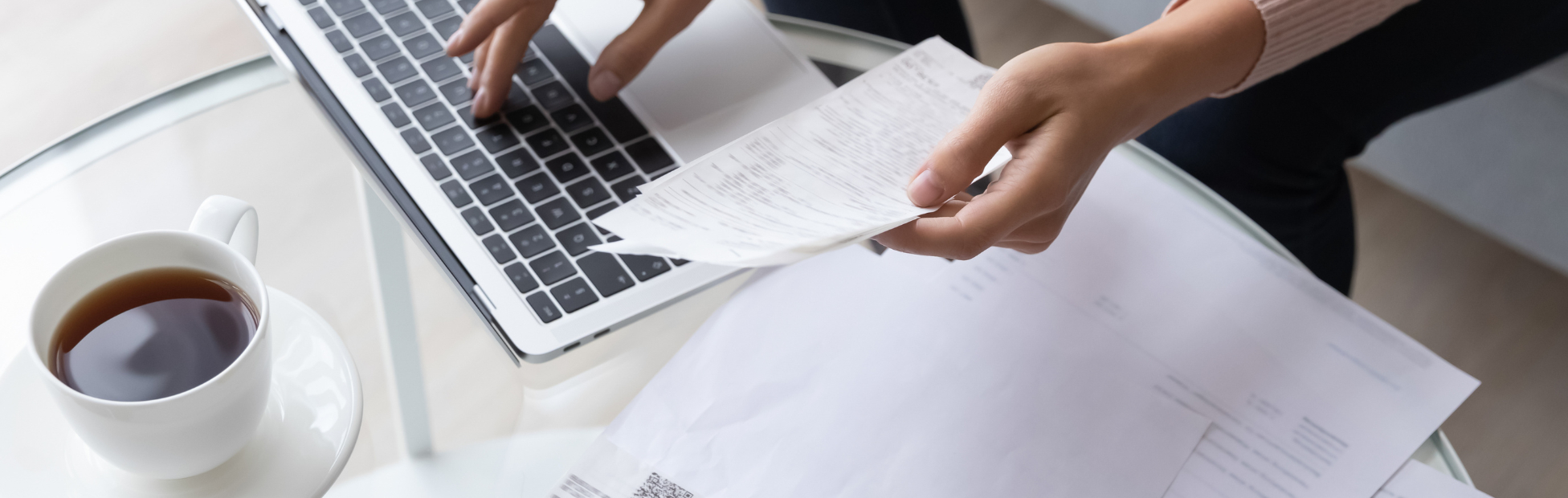 Top down view of a woman at a desk covered with bills and a calculator