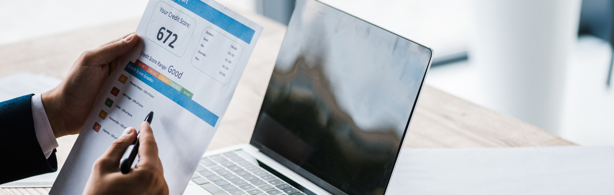 A man with a printed copy of his credit report, reviewing finances online.
