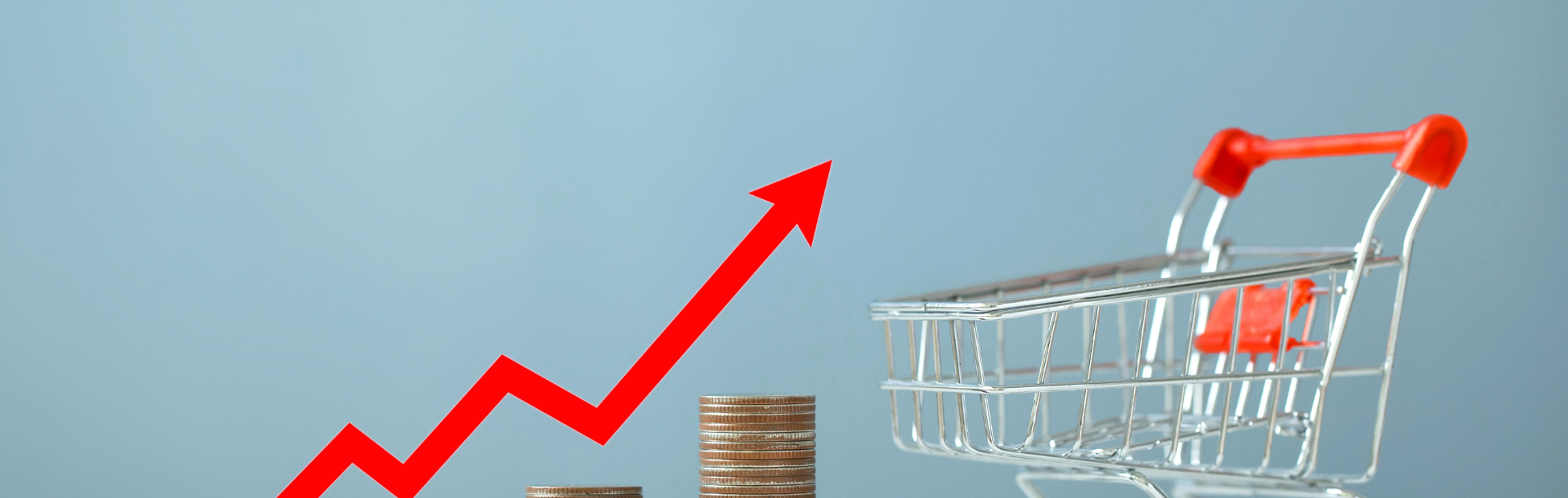 Red inflationary arrow rising up beside a miniature shopping cart
