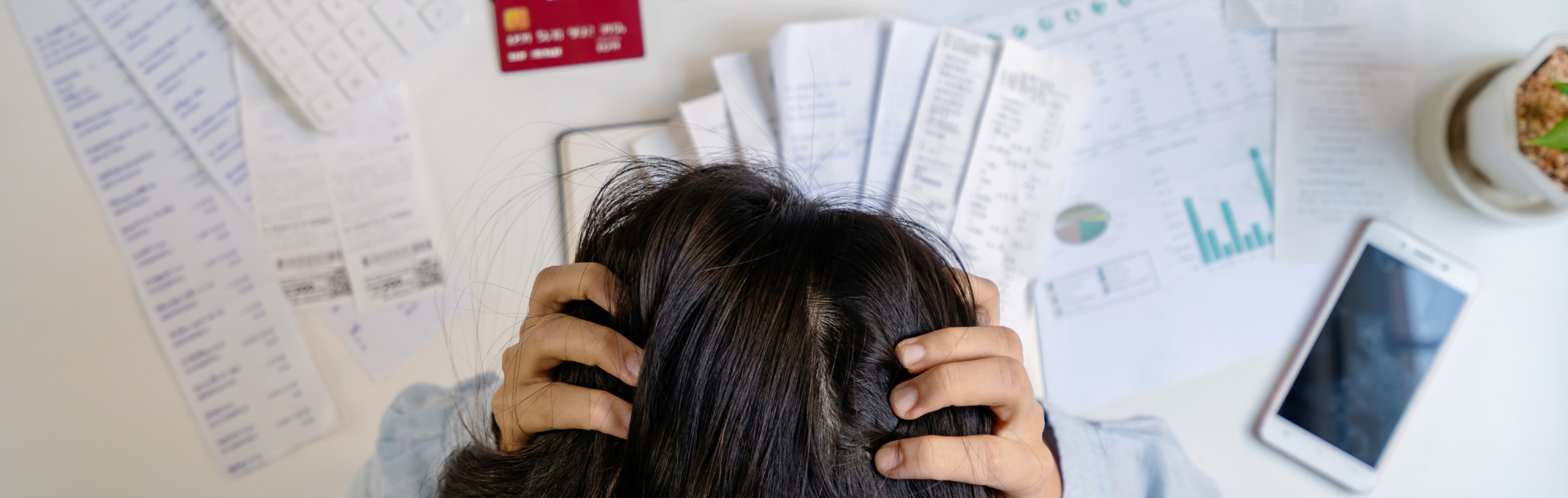 Stressed young woman surrounded by bills, calculating monthly expenses
