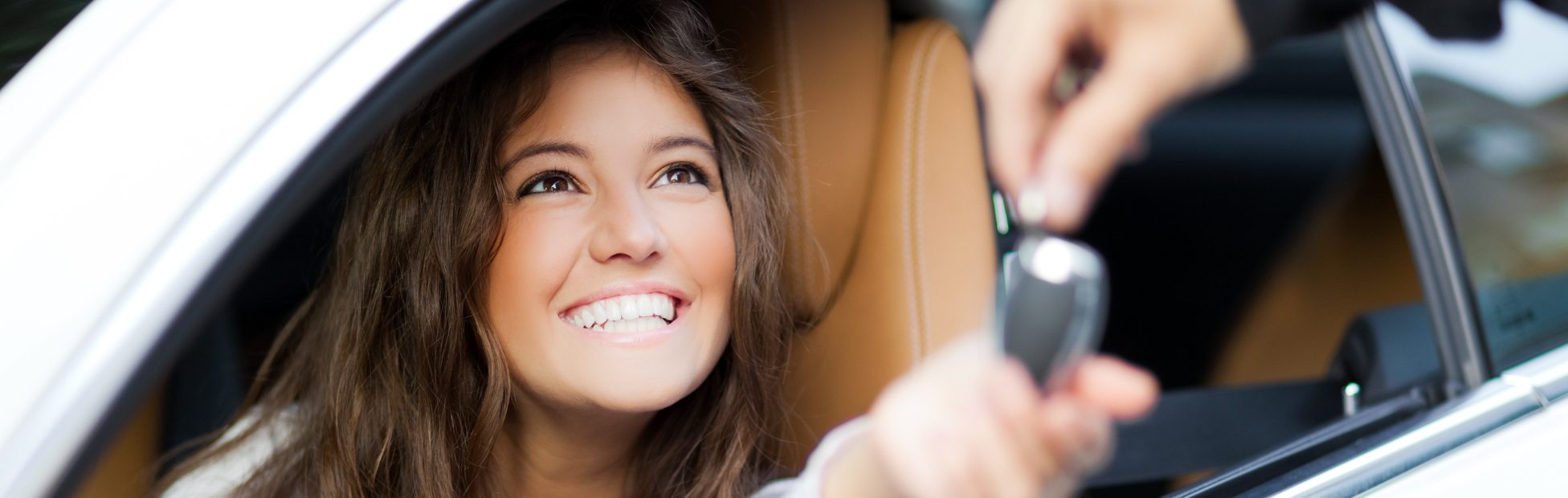 Smiling young brunette woman receiving the keys to her new car