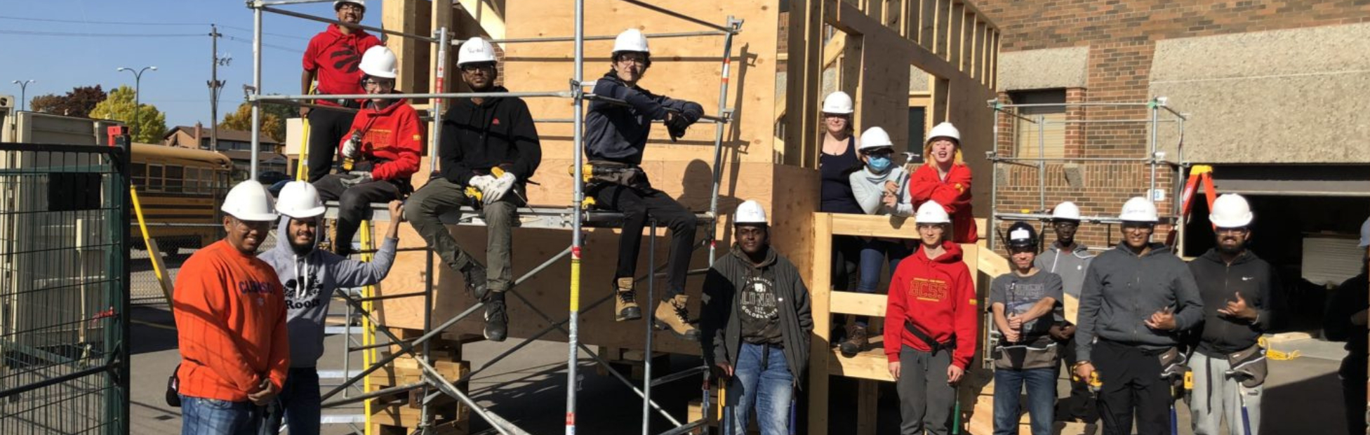 A group of students and teachers around an in-progress home build