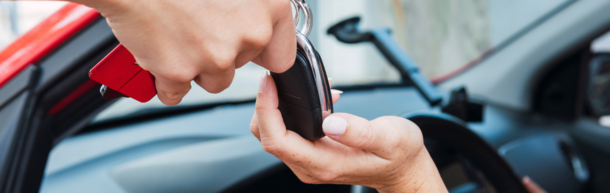 Car salesman handing keys to person in a red vehicle.