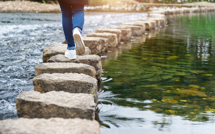 Person crossing a river on stepping stones
