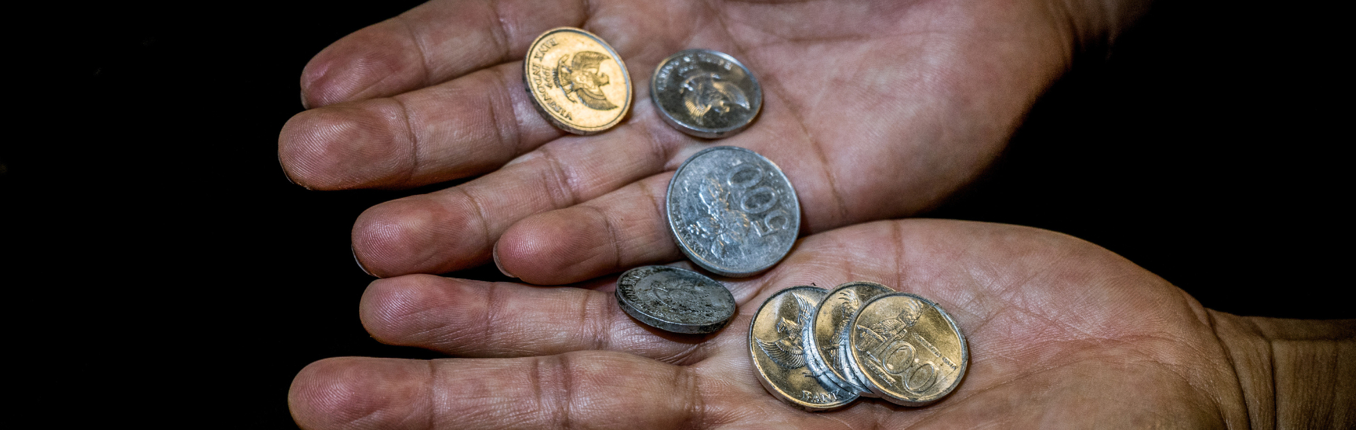 A few coins in the hands of an aging woman.