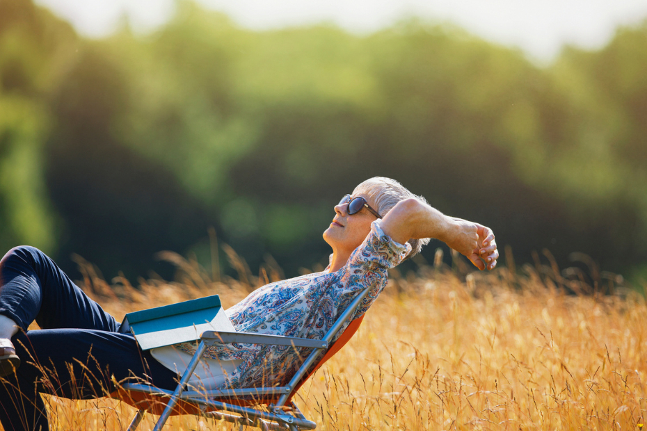 Woman relaxing with book in sunny field.