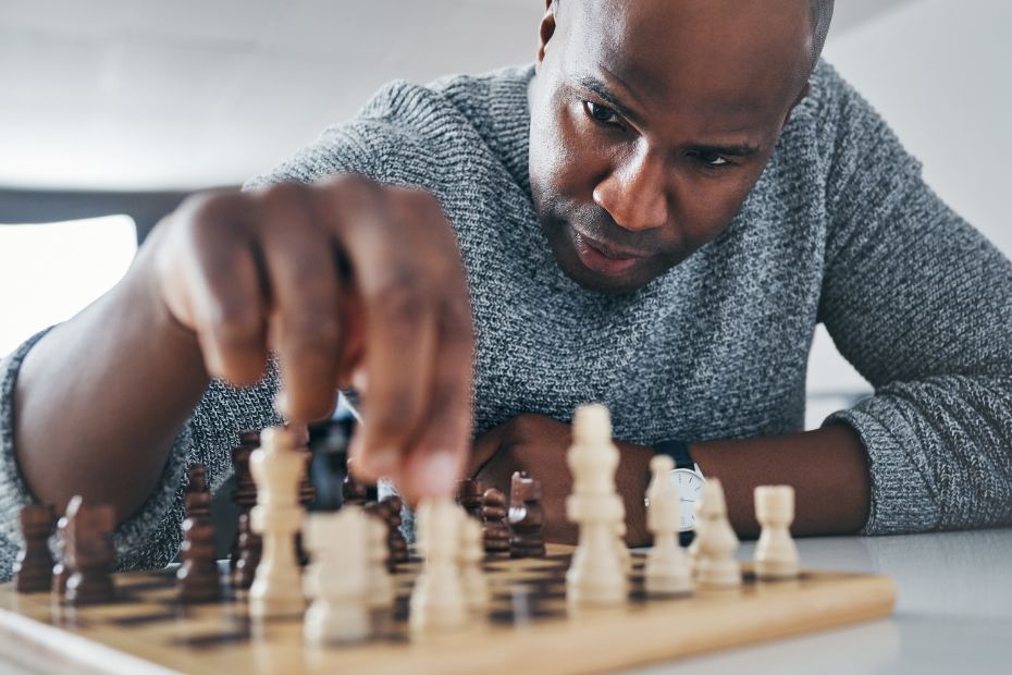 A close-up of a male business owner strategically moving a chess piece