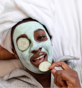 Woman with a face mask and cucumbers on her eye