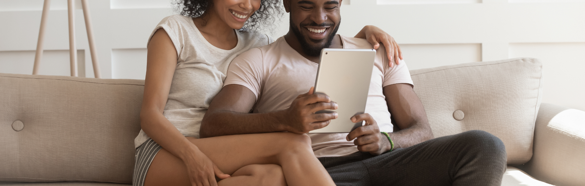 A couple sitting on the couch with a tablet
