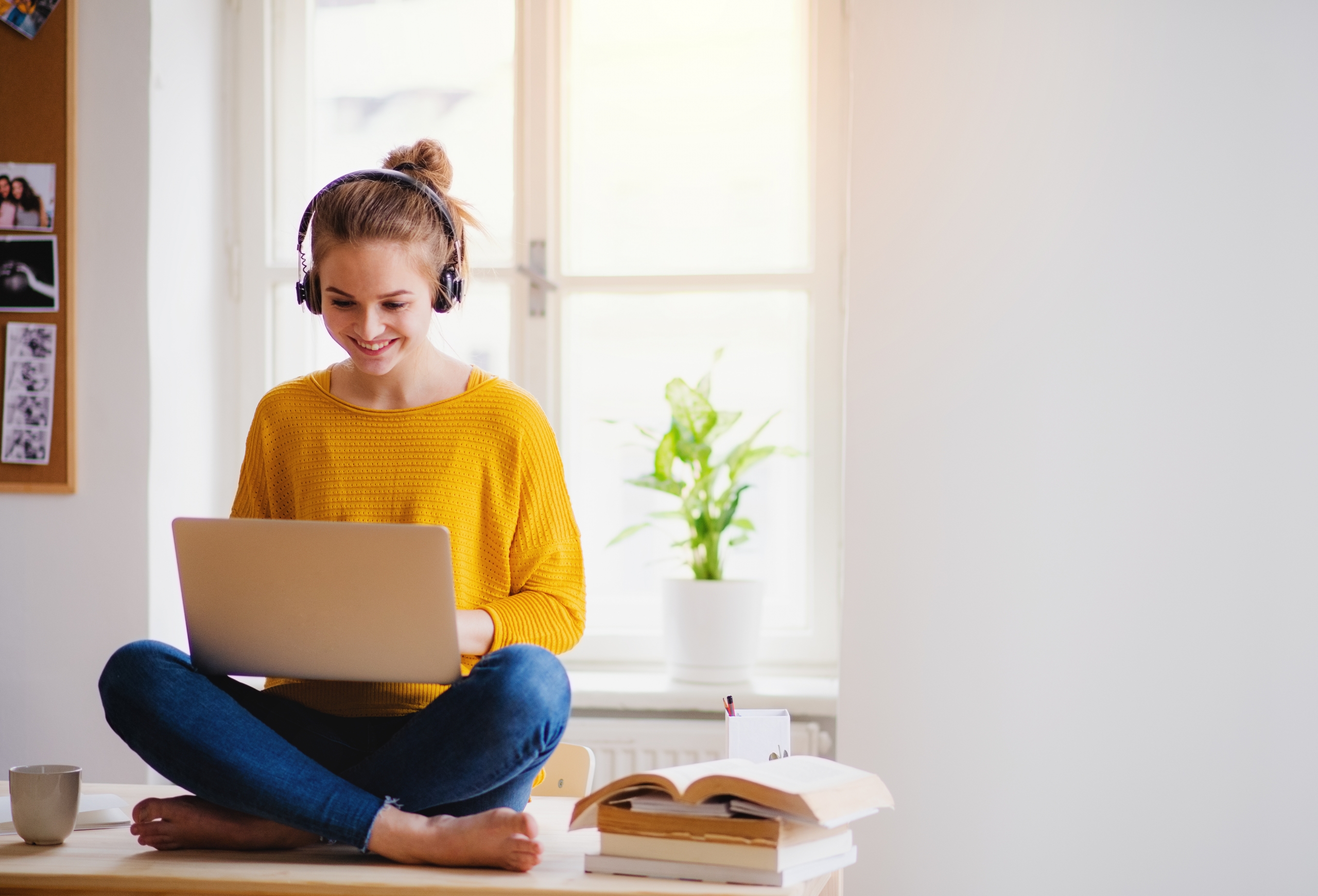 A smiling young female freelancer on her laptop, searching for volunteer opportunities.