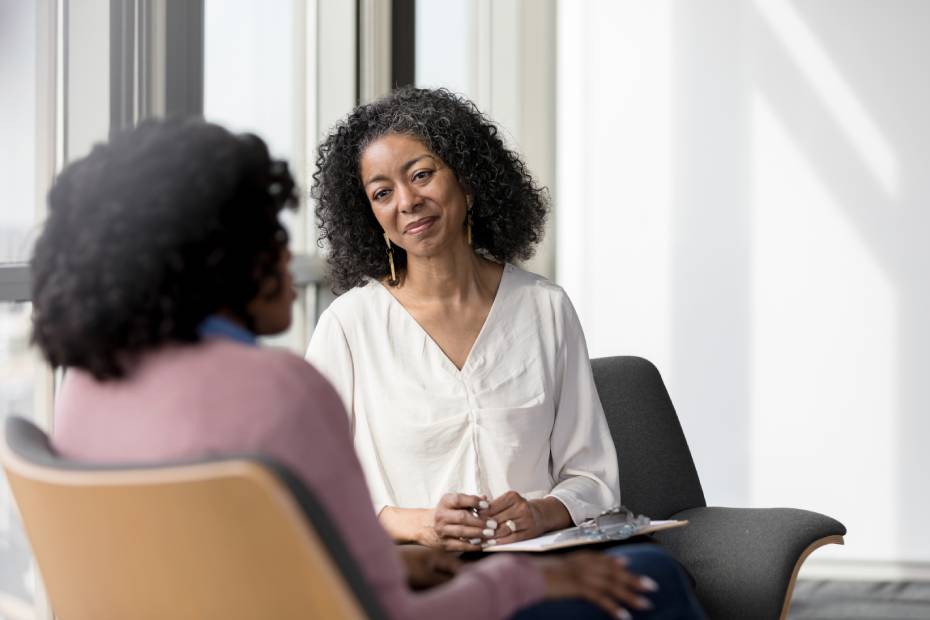 A female therapist listens compassionately to her female patient.