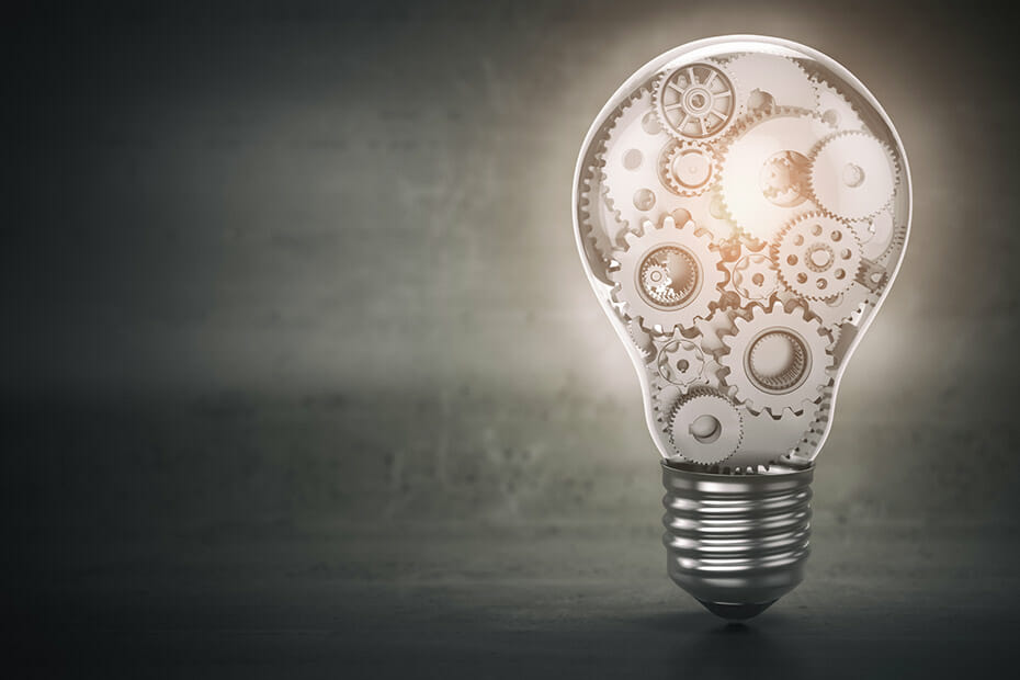 Grey background with lightbulb housing cogs and wheels inside it showing intricate thinking