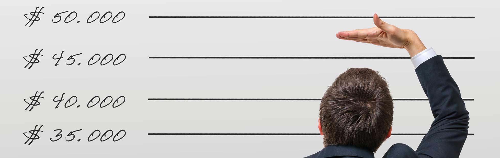 A man measures his height in front of a wall.