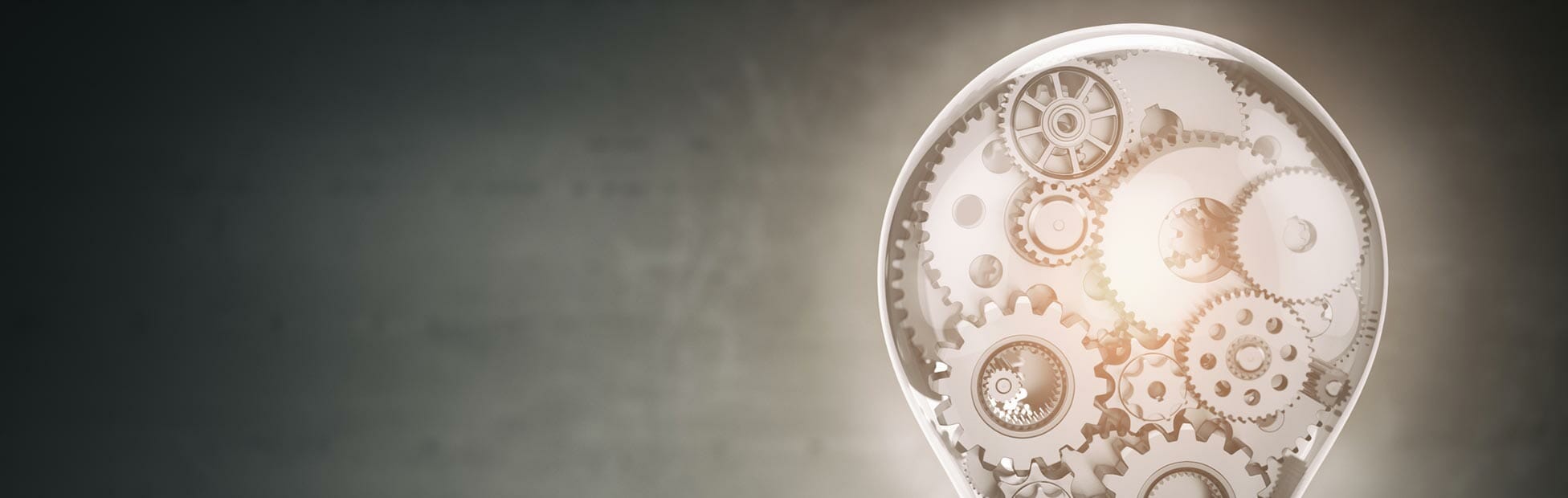 Grey background with lightbulb housing cogs and wheels inside it showing intricate thinking